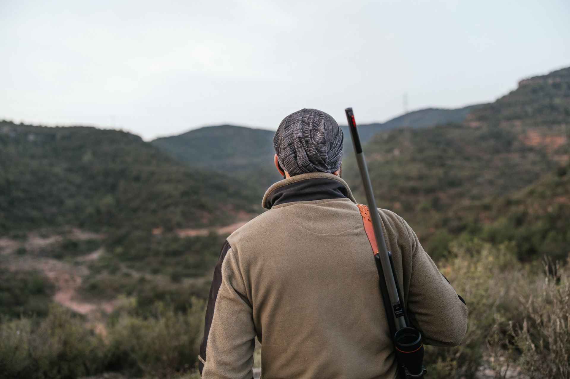 Hunter with rifle overlooking a rugged mountain valley